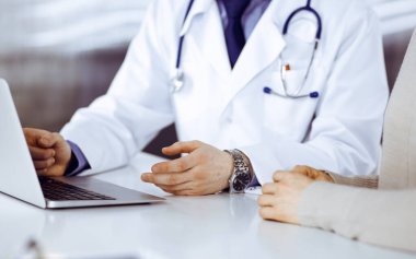 Bilinmeyen erkek doktor ve hasta kadın klinikte oturup dizüstü bilgisayar kullanırken bir şeyler tartışıyorlar. Hastanedeki en iyi sağlık hizmeti, ilaç, salgın durdurma.