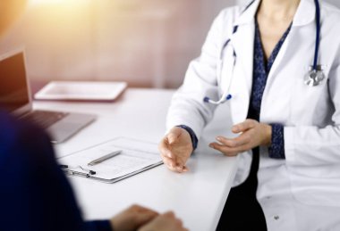 Tanımlanamayan kadın-doktor, bir klinikteki güneşli dolapta birlikte otururken hastasıyla teşhisi hakkında konuşuyor. İşyerindeki doktor, yakın plan. Mükemmel tıbbi servis.