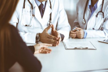 Meçhul erkek doktor modern klinikte otururken hasta kadını dinliyor. Mükemmel tıbbi servis, Coronavirus salgını sırasında ilaç konsepti. Covid 2019