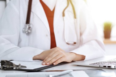 İş yerindeki masada oturan kimliği belirsiz kadın-doktor, ellerinizi yakın tutun. Tıp konsepti