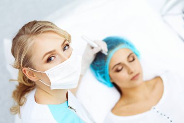 Kadın yüzüne kaş dövmesi yapan profesyonel bir güzellik uzmanı. Güzellik salonunda kalıcı kaş makyajı, yakın çekim. Kozmetoloji tedavisi