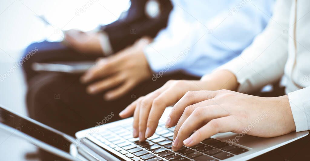 Group of business people working in office, close-up. Businesswoman typing on laptop. Conference, training or meeting concepts