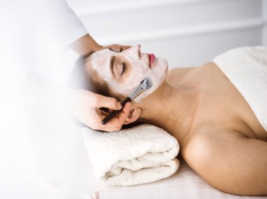 Güzel esmer kadın kozmetik maske takmaktan zevk alıyor. Rahat ve bisküvi dolu. Tıp ve kaplıca merkezi kavramlarında rahatlatıcı tedavi