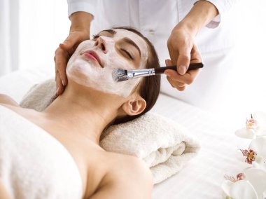 Güzel esmer kadın kozmetik maske takmaktan zevk alıyor. Rahat ve bisküvi dolu. Tıp ve kaplıca merkezi kavramlarında rahatlatıcı tedavi