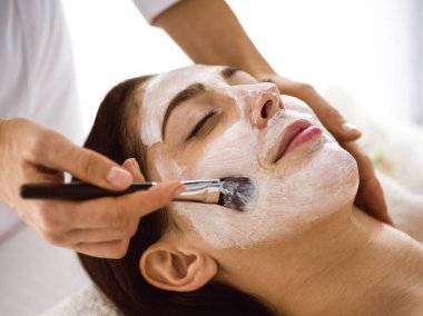 Güzel esmer kadın kozmetik maske takmaktan zevk alıyor. Rahat ve bisküvi dolu. Tıp ve kaplıca merkezi kavramlarında rahatlatıcı tedavi