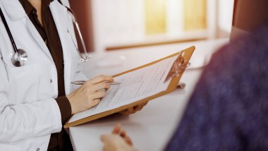 Doktor ve hasta güneşli klinikte otururken sağlık muayenesini tartışıyorlar. Hastanede mükemmel bir tıbbi hizmet.