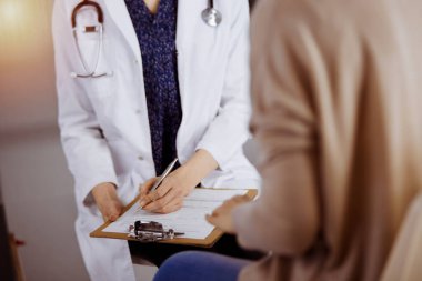 Doktor ve hasta güneşli klinikte otururken sağlık muayenesini tartışıyorlar. Hastanede mükemmel bir tıbbi hizmet.