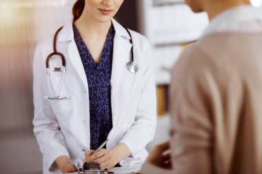 Doktor ve hasta güneşli klinikte otururken sağlık muayenesini tartışıyorlar. Hastanede mükemmel bir tıbbi hizmet.