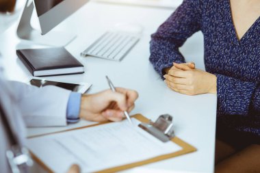 Bilinmeyen sakallı doktor ve hasta kadın güneşli klinikte otururken sağlık muayenesini tartışıyorlar.