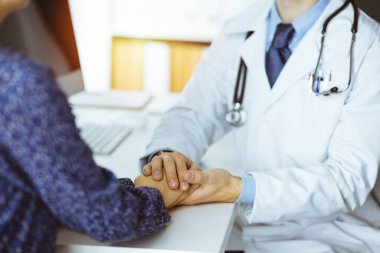 Dost canlısı sakallı doktor, kadın hastasına güvence veriyor, yakın plan. Tıp etiği ve güven kavramı, tıp teması