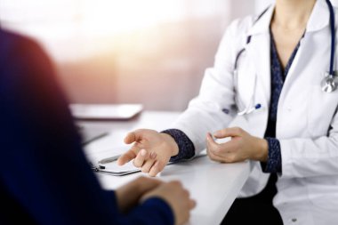 Tanımlanamayan kadın-doktor, bir klinikteki güneşli dolapta birlikte otururken hastasıyla teşhisi hakkında konuşuyor. İşyerindeki doktor, yakın plan. Mükemmel tıbbi servis.