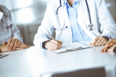 Bilinmeyen kadın-doktor ve erkek meslektaşı modern klinikte masa başında otururken hasta kadına danışıyorlar. Mükemmel bir tıbbi hizmet, Coronavirus salgını sırasında ilaç. Covid 2019