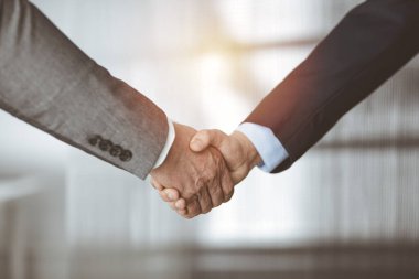 Güneşli ofiste el sıkışan iş adamları, yakın plan. El sıkışma ve pazarlama