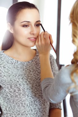 Profesyonel makyöz güzel genç bir kadınla çalışıyor. Gelin, moda ya da çıplak stil