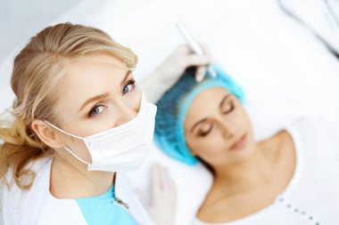 Kadın yüzüne kaş dövmesi yapan profesyonel bir güzellik uzmanı. Güzellik salonunda kalıcı kaş makyajı, yakın çekim. Kozmetoloji tedavisi