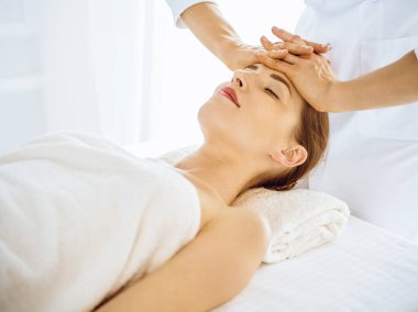 Kaplıca merkezinde gözleri kapalı yüz masajından hoşlanan güzel bir kadın.