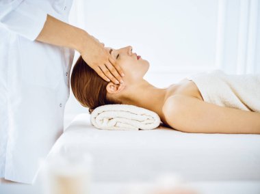 Kaplıca merkezinde gözleri kapalı yüz masajından hoşlanan güzel bir kadın.