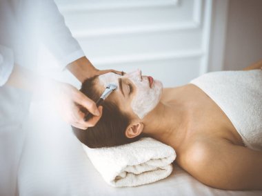 Güzel esmer kadın kapalı gözlerle kozmetik maske takmaktan zevk alıyor. Tıp ve kaplıca merkezi kavramlarında rahatlatıcı tedavi