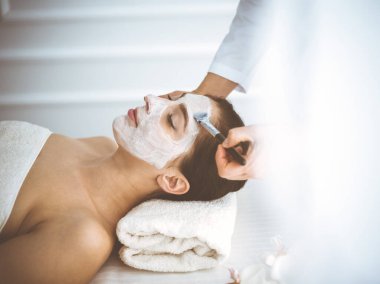 Güzel esmer kadın kapalı gözlerle kozmetik maske takmaktan zevk alıyor. Tıp ve kaplıca merkezi kavramlarında rahatlatıcı tedavi