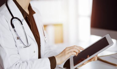 Güneşli klinikte tablet bilgisayar kullanan kimliği belirsiz bir kadın doktor. Hastanede mükemmel bir tıbbi hizmet.