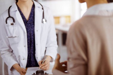 Doktor ve hasta güneşli klinikte otururken sağlık muayenesini tartışıyorlar. Hastanede mükemmel bir tıbbi hizmet.