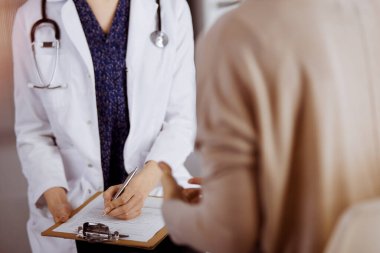 Doktor ve hasta güneşli klinikte otururken sağlık muayenesini tartışıyorlar. Hastanede mükemmel bir tıbbi hizmet.