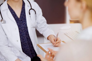 Doktor ve hasta güneşli klinikte otururken sağlık muayenesini tartışıyorlar. Hastanede mükemmel bir tıbbi hizmet.