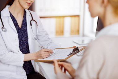 Doktor ve hasta güneşli klinikte otururken sağlık muayenesini tartışıyorlar. Hastanede mükemmel bir tıbbi hizmet.