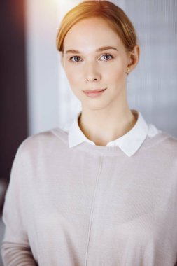 Dost canlısı, sıradan giyinmiş iş kadını dik duruyor. İş vesikalığı ya da ofiste portre