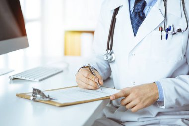 Dost canlısı kızıl sakallı doktor klinikte pano ile oturup yazıyor.