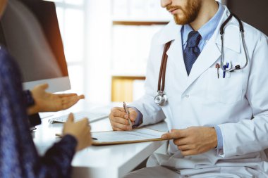 Bilinmeyen sakallı doktor ve hasta kadın güneşli klinikte otururken sağlık muayenesini tartışıyorlar.