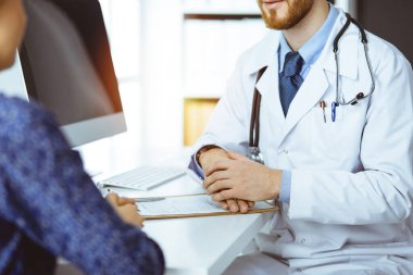 Bilinmeyen sakallı doktor ve hasta kadın güneşli klinikte otururken sağlık muayenesini tartışıyorlar.