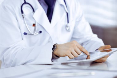 Bilinmeyen erkek doktor klinikteki tablet bilgisayarla yakın planda çalışıyor. İşteki genç doktor. Mükemmel sağlık hizmeti, tıp konsepti