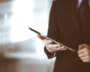 İş adamları yeni projelerini tartışmak için bir tablet bilgisayar kullanıyorlar, modern bir ofiste duruyorlar. İş yerinde iş arkadaşı olan tanınmamış bir iş adamı ya da erkek girişimci. Takım çalışması ve ortaklık