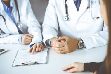 Meçhul erkek doktor modern klinikte otururken hasta kadını dinliyor. Mükemmel tıbbi servis, Coronavirus salgını sırasında ilaç konsepti. Covid 2019