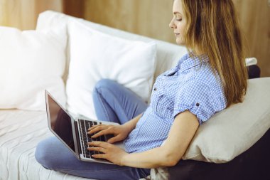 Covid-19 karantinası sırasında dizüstü bilgisayarda çalışan genç bir kadın. Coronavirus salgınında ev konseptinde kal