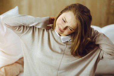 Yorgun bir kadın masaj yapıyor, boynu ağrıyor, kasları geriliyor bilgisayar çalışmalarından dolayı yorgun düşmüş. Coronavirus salgını sırasında evde konsept kal