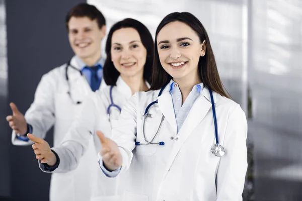 Doctors are standing as a team while offering their helping hands for shaking hand or saving peoples life. Physicians are ready to help their patients. Medical help, insurance in health care, best