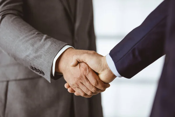 Business people in office suits standing and shaking hands, close-up. Business communication concept. Handshake and marketing