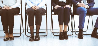 Bir grup iş adamı ofiste oturup iş görüşmesini beklerken cihazları kullanıyor, yakın plan. Adam toplama ve kafa avlama kavramları