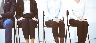 Bir grup iş adamı ofiste oturup iş görüşmesini beklerken cihazları kullanıyor, yakın plan. Adam toplama ve kafa avlama kavramları