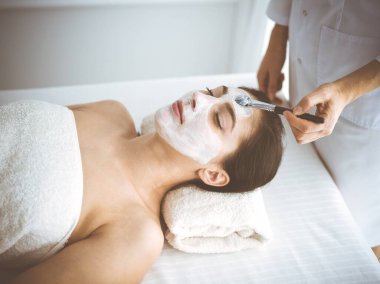 Güzel esmer kadın kapalı gözlerle kozmetik maske takmaktan zevk alıyor. Tıp ve kaplıca merkezi kavramlarında rahatlatıcı tedavi