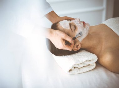 Güzel esmer kadın kapalı gözlerle kozmetik maske takmaktan zevk alıyor. Tıp ve kaplıca merkezi kavramlarında rahatlatıcı tedavi