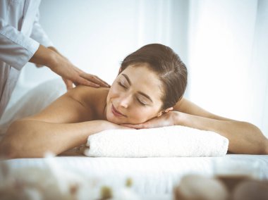 Güzel esmer kadın sırt masajından hoşlanıyor. Gözleri kapalı ve mutlu. Spa ve tıp konsepti