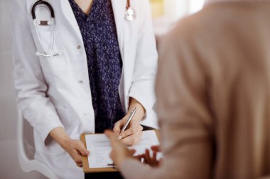 Doktor ve hasta güneşli klinikte otururken sağlık muayenesini tartışıyorlar. Hastanede mükemmel bir tıbbi hizmet.