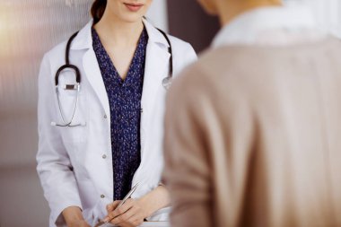 Doktor ve hasta güneşli klinikte otururken sağlık muayenesini tartışıyorlar. Hastanede mükemmel bir tıbbi hizmet.