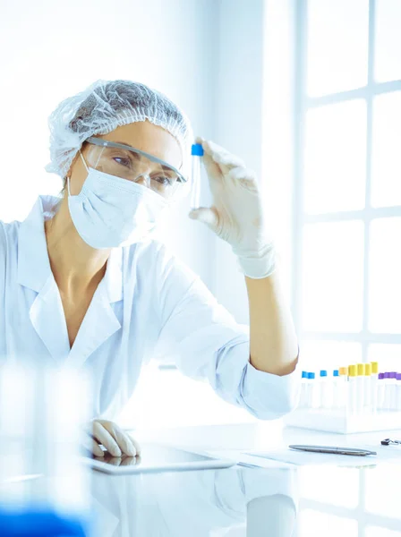 Cientista profissional em óculos de proteção pesquisando tubo com reagentes em laboratório tonificado em azul. Conceitos de medicina e pesquisa científica — Fotografia de Stock
