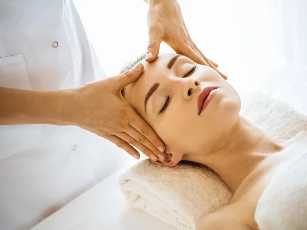 Beautiful woman enjoying facial massage with closed eyes in spa center — Stock Photo, Image