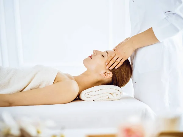 Mulher bonita desfrutando de massagem facial com olhos fechados no centro de spa — Fotografia de Stock