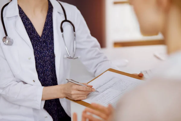 Médecin et patient discutant de l'examen de santé actuel assis dans une clinique ensoleillée. Service médical parfait à l'hôpital — Photo